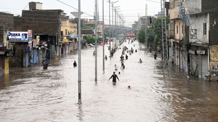 Flood in Pakistan (18 07 2025) (1) People wade through floodwaters in a submerged street in Pakistan. The flooding has caused significant damage to homes and infrastructure in the region. (Source: CNN)
